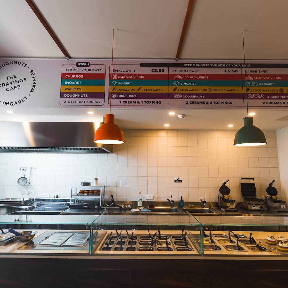 Assortment of freshly baked doughnuts, churros, and waffles at Zwiit Cravings Cafe in St. Julians, Malta, offering a delightful variety of sweet treats.