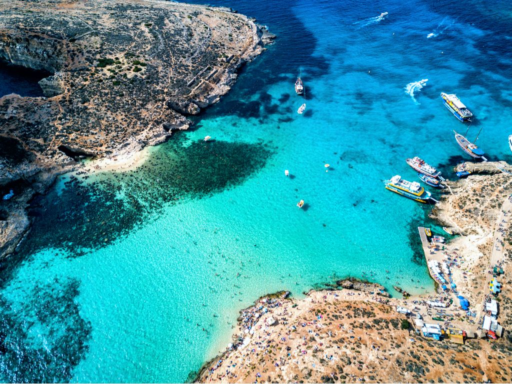 Blue Lagoon, Comino: A breathtaking view of the crystal-clear turquoise waters of the Blue Lagoon, surrounded by rugged cliffs and bathed in sunlight.