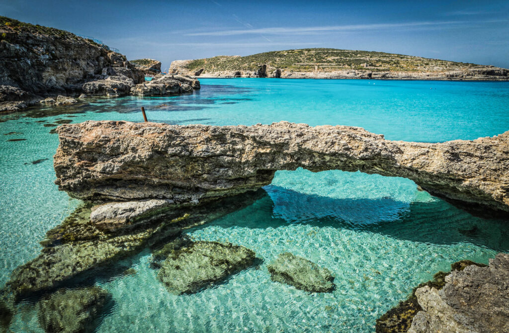 Blue Lagoon, Comino Island, Malta: A stunning aerial view of the famous turquoise lagoon surrounded by rugged cliffs. The crystal-clear waters reveal the sandy seabed below, inviting visitors to swim, snorkel, and enjoy the natural beauty of this idyllic spot in the Mediterranean.




