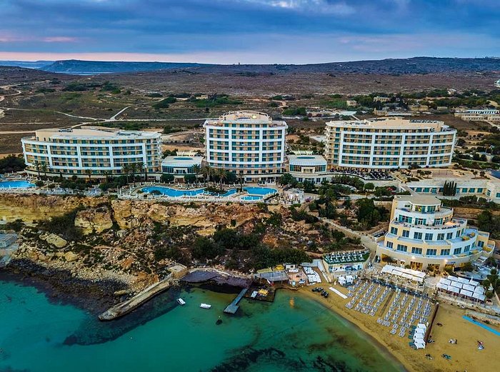 Aerial view of Golden Bay Beach Resort & Spa, Malta: turquoise sea, golden sands, lush greenery.