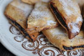  An enticing array of Imqaret, traditional Maltese pastries, showcasing their golden-brown diamond-shaped crusts filled with a sweet and sticky date mixture. The Imqaret are arranged neatly on a serving platter, highlighting their irresistible aroma and deliciously chewy texture.