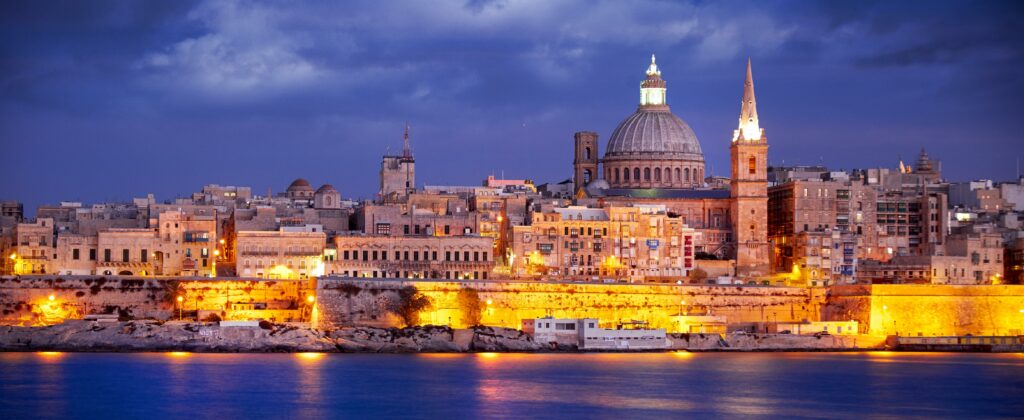 Valletta skyline illuminated at night with historic buildings and waterfront views