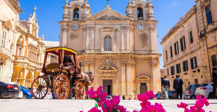 The exterior of the Co-Cathedral of St. Paul in Mdina, Malta, bathed in warm sunlight against a clear blue sky. The imposing facade of the cathedral features intricate Baroque architecture, with ornate carvings, towering spires, and a grand entrance adorned with statues. Visitors gather outside, marveling at the cathedral's majestic beauty and historical significance, as it stands as a timeless symbol of faith and heritage in the heart of the Silent City.