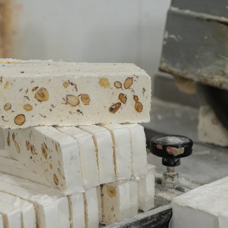 A mouthwatering display of Qubbajt, traditional Maltese nougat, featuring blocks of chewy confection made from honey, sugar, and almonds, with variations including both white and brown nougat. The Qubbajt is presented on a rustic wooden board, showcasing its rich texture and nutty sweetness, making it a delightful treat for any occasion.




