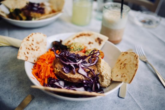 A platter of creamy hummus surrounded by an assortment of fresh vegetable sticks, such as carrots, cucumber, and bell peppers, offering a colourful and nutritious snack option.