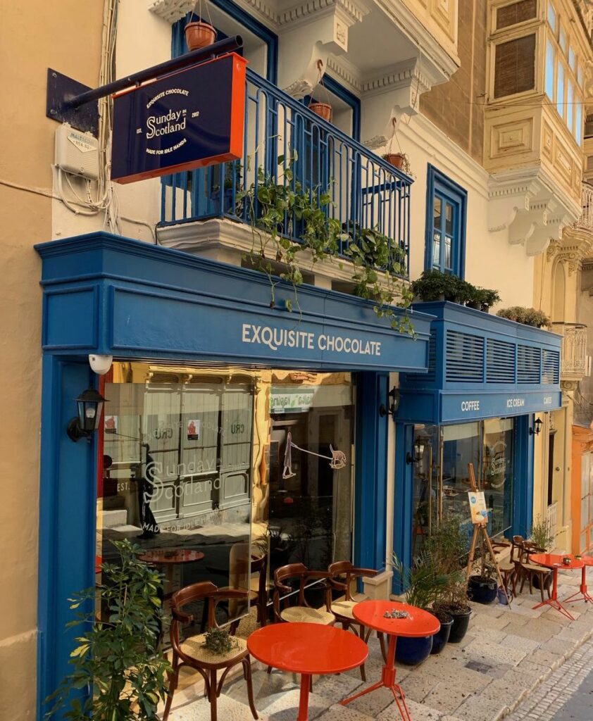 The exterior of Sunday Scotland café, with charming façade adorned with potted plants and inviting seating, promising a delightful experience for patrons seeking vegan-friendly options in Valletta.