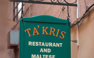 Warm and inviting ambiance at Ta' Kris Restaurant in Sliema, Malta, with a table set for traditional Maltese dining, showcasing hearty dishes and local flavors.