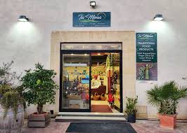 Entrance and interior view of Ta' Mena restaurant in Gozo, showcasing a delicious spread of traditional Maltese cuisine.